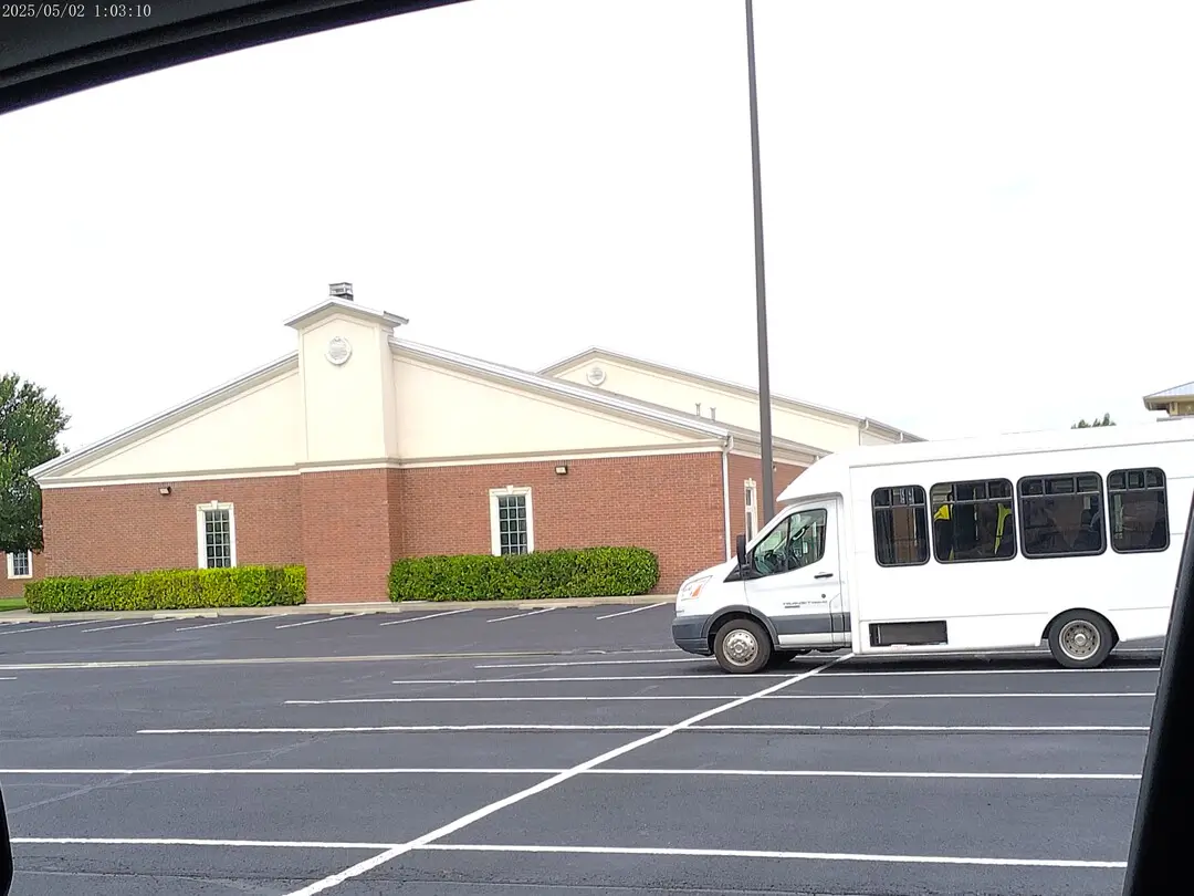 Brick building at Church of Christ of the Colonies with a church van out front