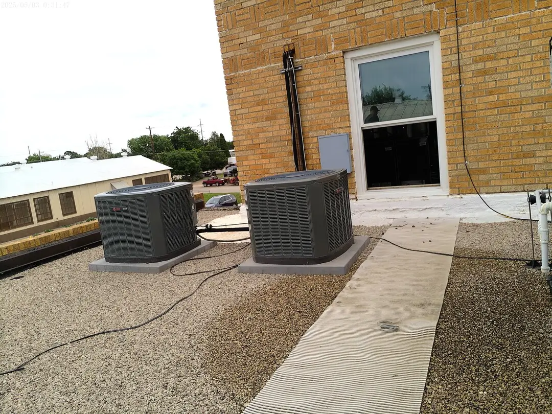 Two condensing units on the DPS building roof beside a window