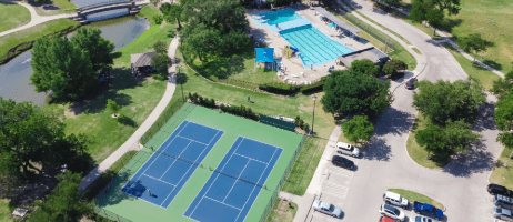 Aerial view of a recreation complex with tennis courts, an outdoor pool, and walking paths