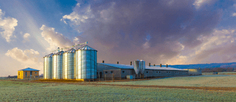 Long metal agricultural building beside grain bins at sunset